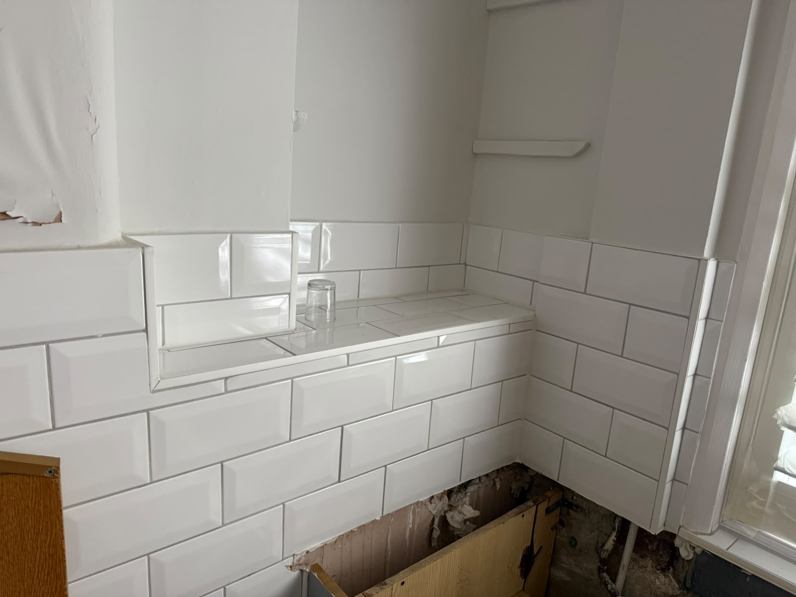 Metro wall tiling in progress around a bathroom window