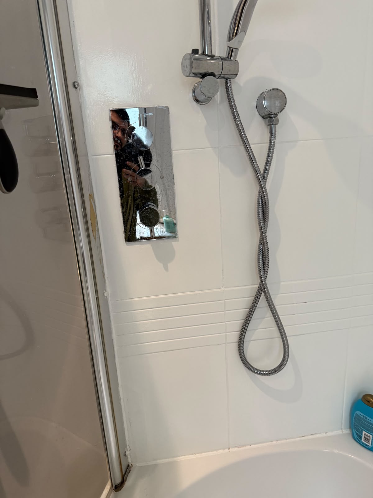 Chrome shower valve and riser fitted in a white tiled shower