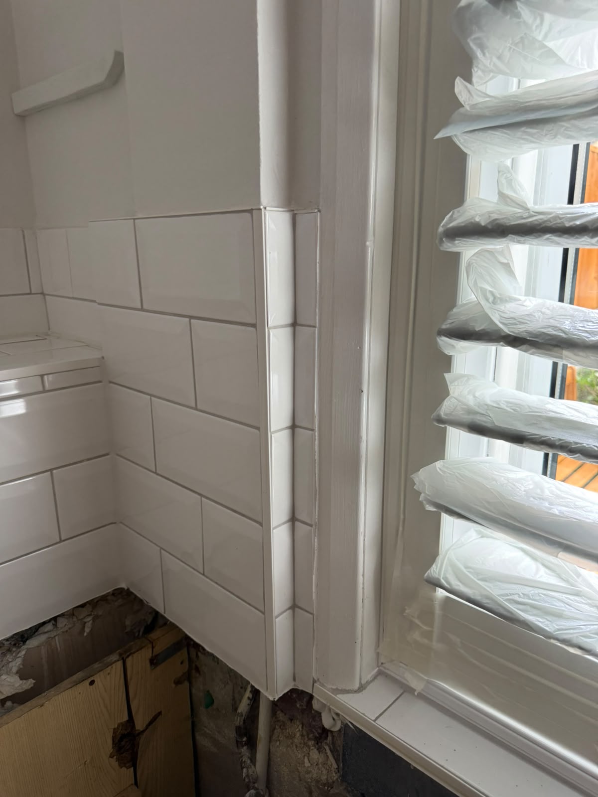 Bevelled metro tiles fitted around a bathroom window reveal