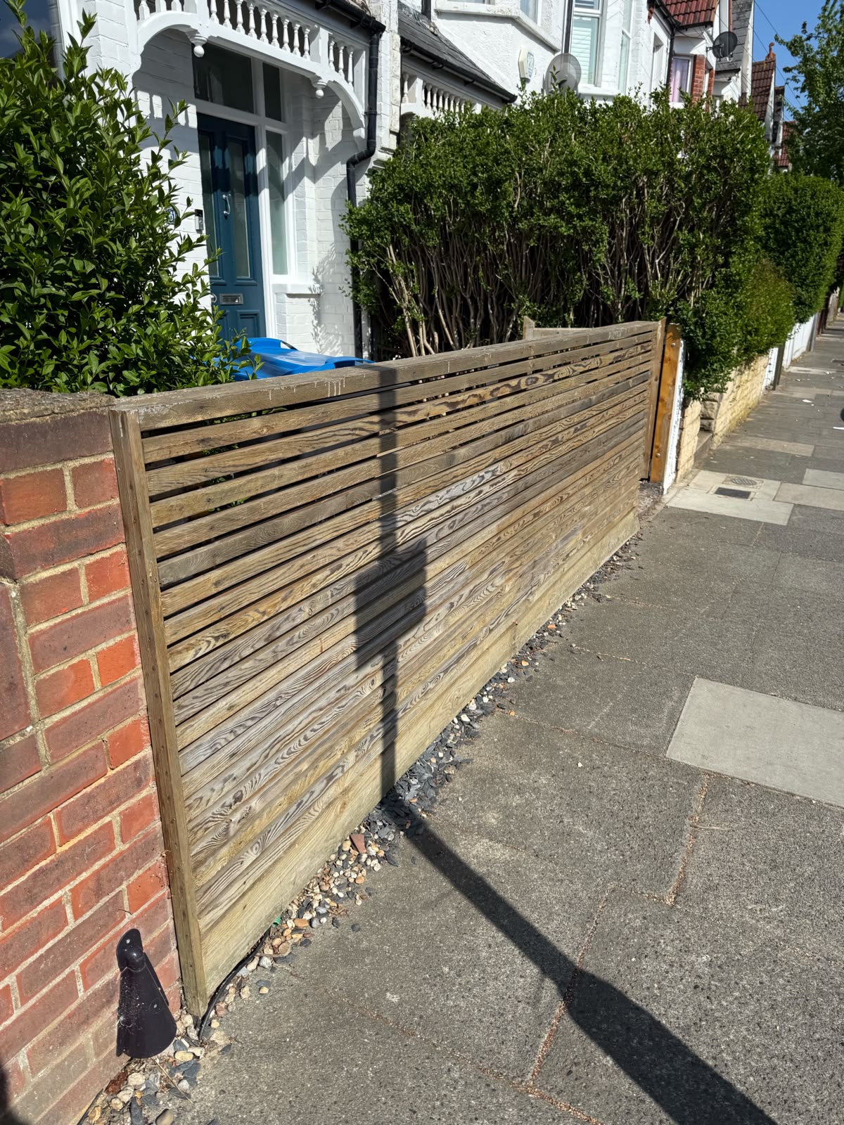 Horizontal slatted fence fitted along a front garden wall